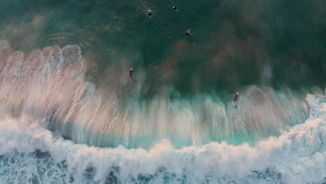 Surfistas-En-La-Ola-En-La-Playa-De-Llandudno,-Ciudad-Del-Cabo-Al-Atardecer---Antena-Arriba-Hacia-Abajo