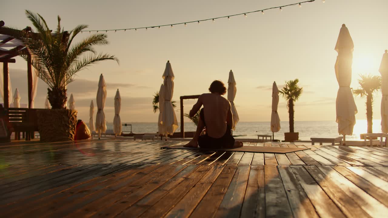 En yogi, der sidder på stranden ved solopgang. Morgenstrand, harmoni mellem krop og sind.