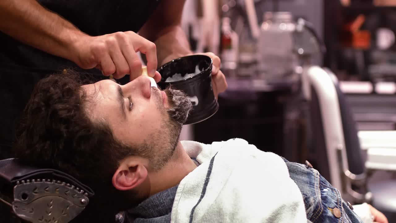Mand får barberet sit skæg med barberkost i barbershoppen