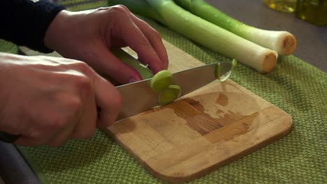 Cu-Chef-Masculino-Preparando-Puerros-Frescos,-Cortándolos-Con-Un-Cuchillo-Afilado-Para-Crear-Un-Plato