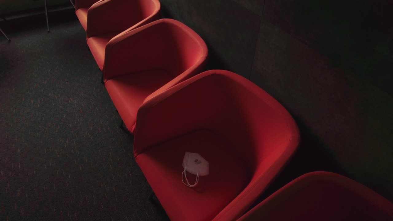 Empty red armchairs in a hospital room with carpets with a forgotten respirator