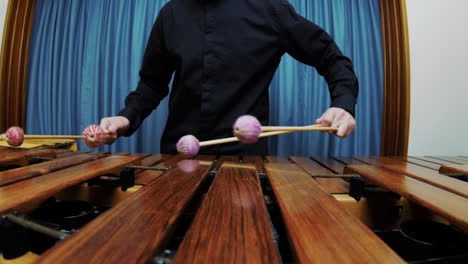 a male percussionist is playing tremolo on marimba wearing a black shirt