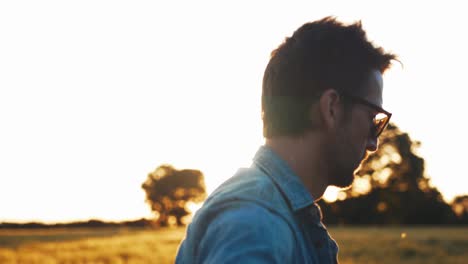 Musician-strumming-guitar-in-field-at-sunset