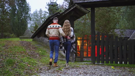 backside view of a young couple. lovely people returning from the date outdoors in warm autumn day. back view of a pretty couple coming into the yard of the cottage.
