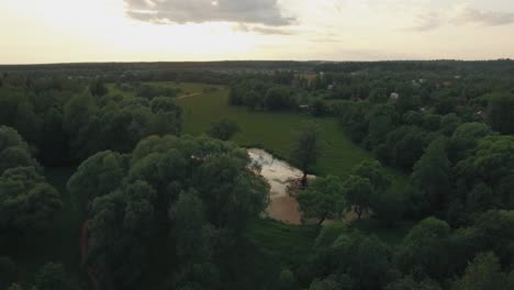 Vista-Del-Lago-Del-Bosque-Y-Casas-De-Campo-Contra-El-Cielo-Azul-Con-Sol-Y-Nubes-Al-Atardecer-En-Verano-Rusia