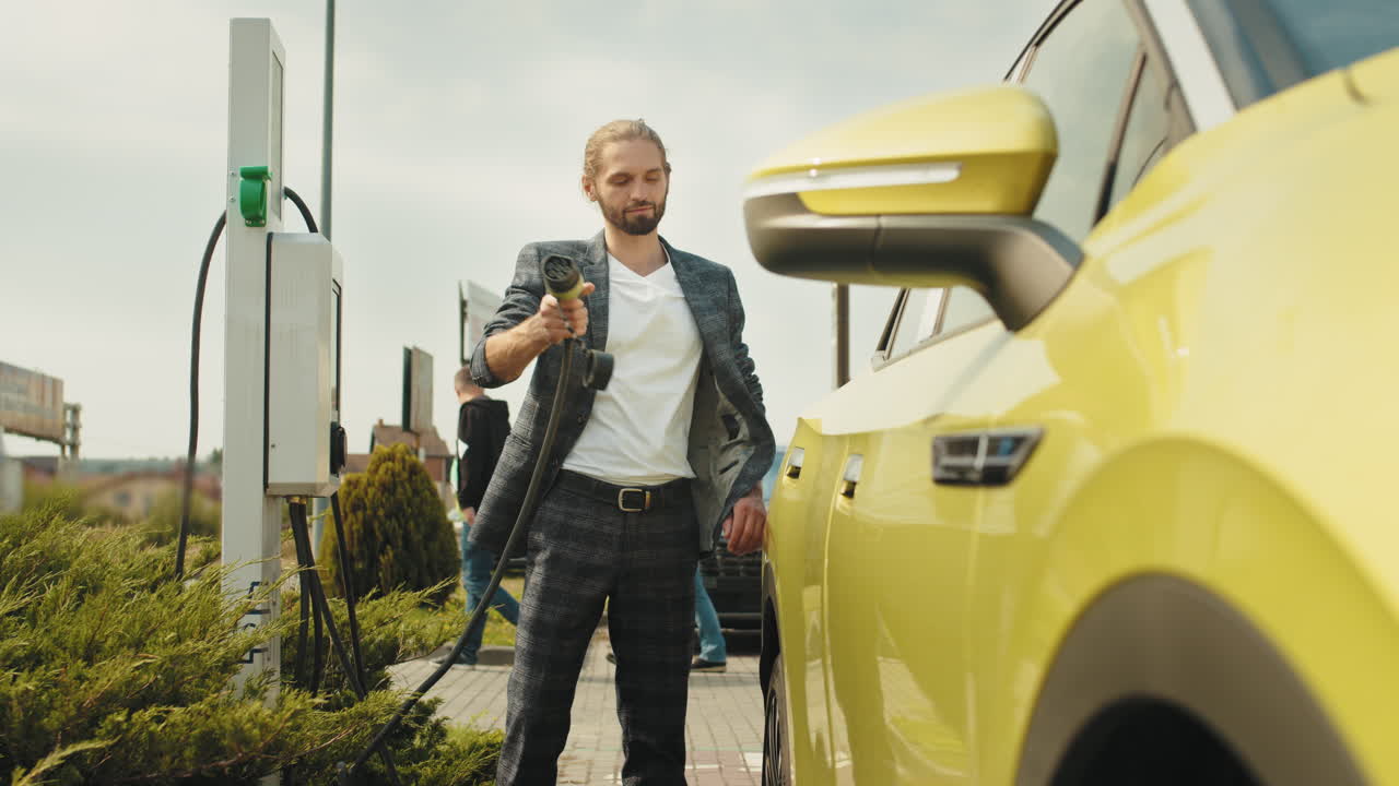 Uomo che carica l'auto elettrica alla stazione di ricarica