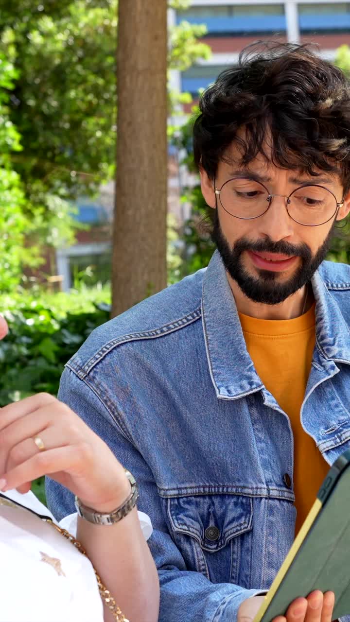 People conversing while using a tablet in a park