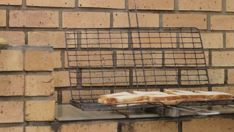 elderley man placing sandwiches on a grill to barbecue for lunch