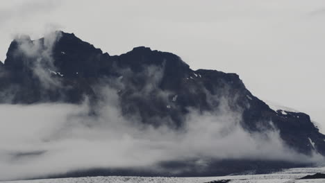 cinematic epic shot of volcanic cloud-covered mountain ranges in fjallsárlón iceland