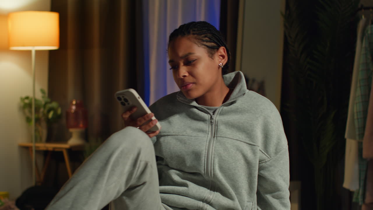 Young Woman Looking at Phone in Bedroom at Night