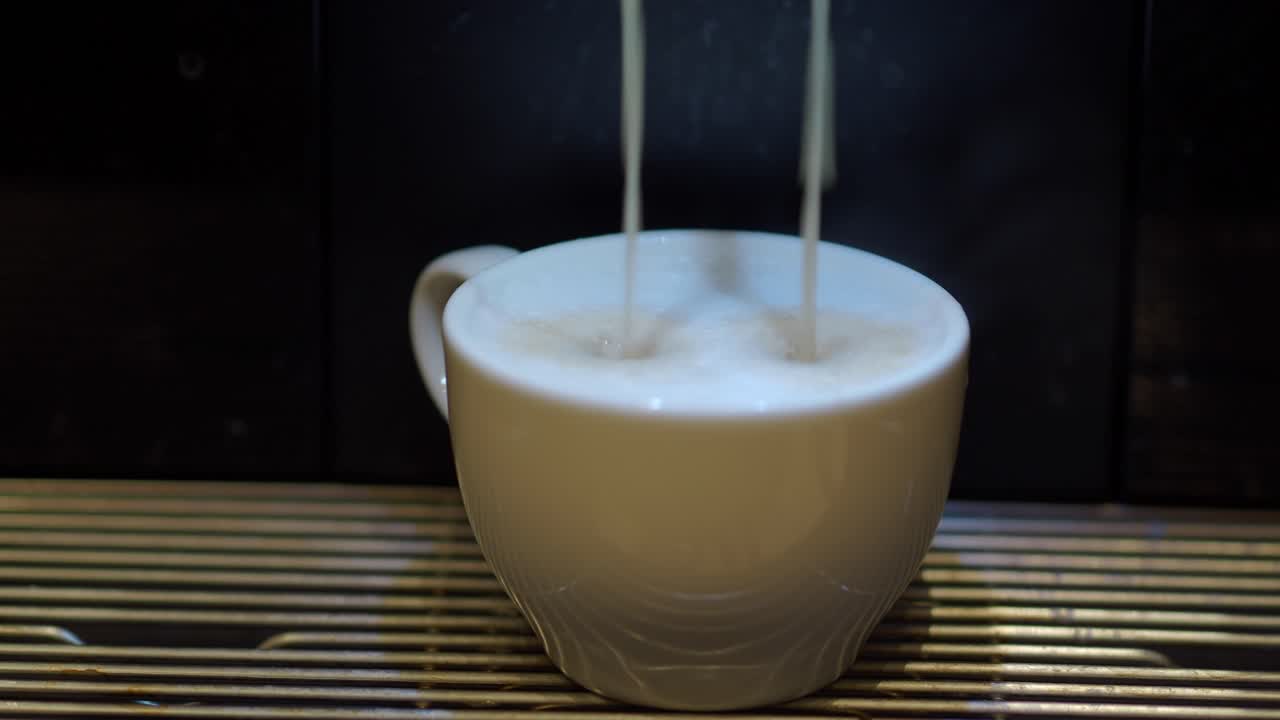 エスプレッソマシンで白いカップにコーヒーが抽出される様子をクローズアップ