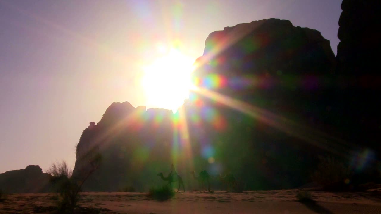 낙타 열차가 요르단 와디럼에서 사우디 사막을 가로지르는 동안 사막의 일출을 가로질러 팬