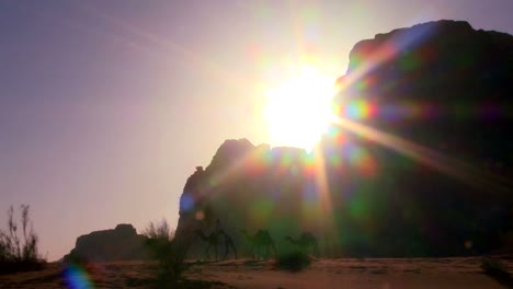 Pan-A-Través-De-Un-Amanecer-En-El-Desierto-Como-Un-Tren-De-Camellos-Cruza-El-Desierto-De-Arabia-En-Wadi-Rum-Jordania