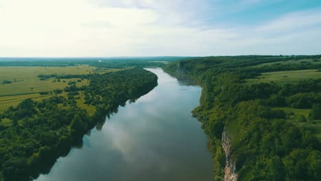 the sky is reflected on the calm surface of the water in the river on a sunny day. steep shores of the reservoir are covered with dense vegetation. the concept of taking care of nature.