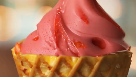 close-up of pink and vanilla ice cream in a waffle cone