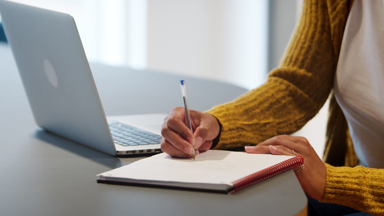 Close up of the hands of a businesswoman writing notes in an office, selective focus