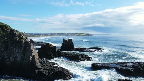 Unique-FPV-flying-past-towering-basalt-rock-formation-above-a-rugged-seascape-coastline