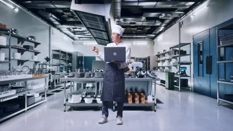 chef usando una computadora portátil en una cocina comercial moderna