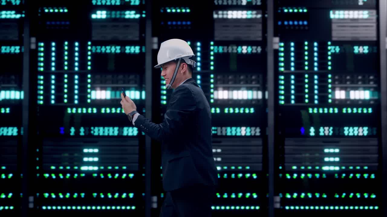 Side View of Asian Businessman Use Smartphone, Video Call While Walking in Server Room Data Center