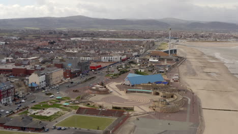 an aerial view of rhyl promenade and seafront on a cloudy day, flying over the promenade towards kinmel bay while zooming in, north wales, uk