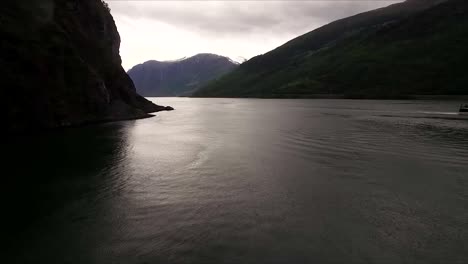 Beautiful-drone-shot-flying-over-water-towards-the-scenic-views-of-Norway-on-a-gloom,-cloudy-day