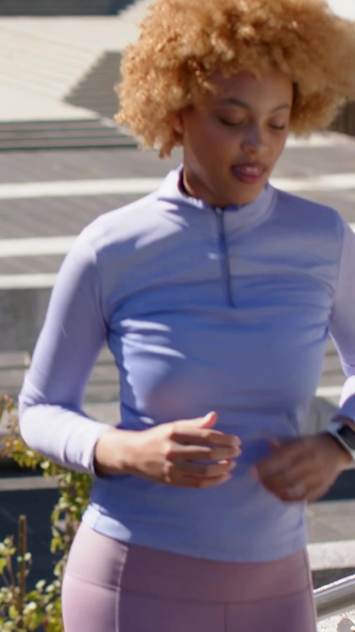 Vertical video: Running woman training in lilac top checking watch at plaza, male joining alongside