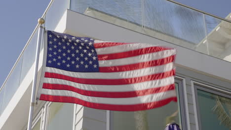 a close up shot of american flag waving in front of a house