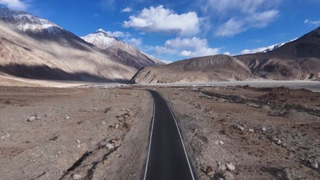 aerial drone shot capturing a vehicle navigating narrow passes and rocky landscapes in ladakh.