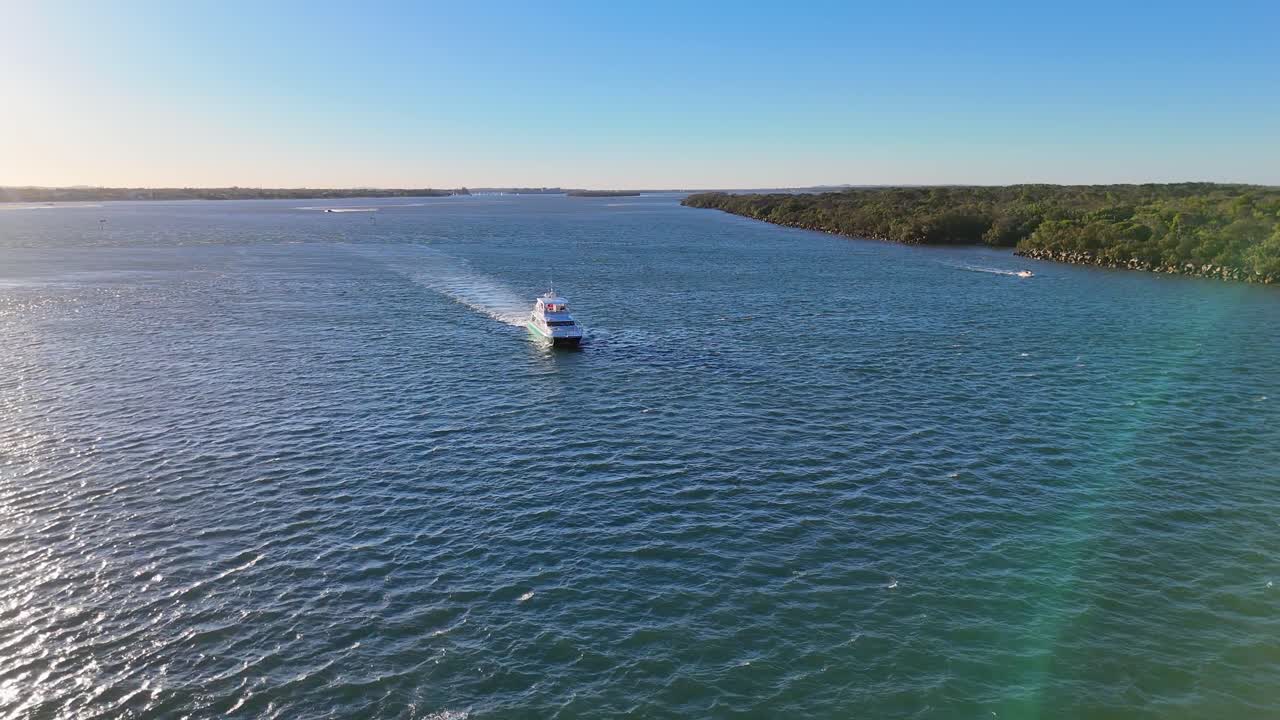 Aerial view of a yacht navigating clear blue waters near Gold Coast, Australia, under bright sunlight with gentle waves