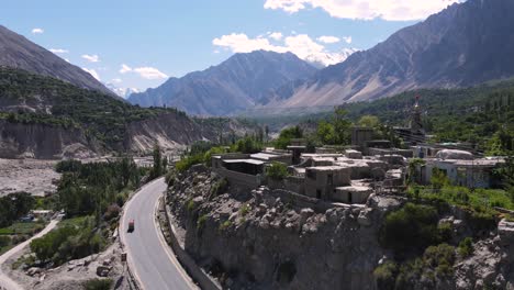 aerial view of rickshaw vehicle on karakoram highway in northern pakistan, hunza valley village and landscape, drone shot