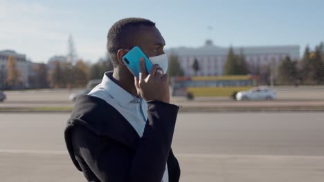 man wearing mask talking on phone in city