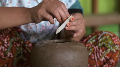 woman smoothing clay pot