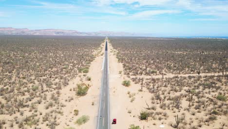 straight desert highway cutting through baja california sur's dry, cactus-filled terrain