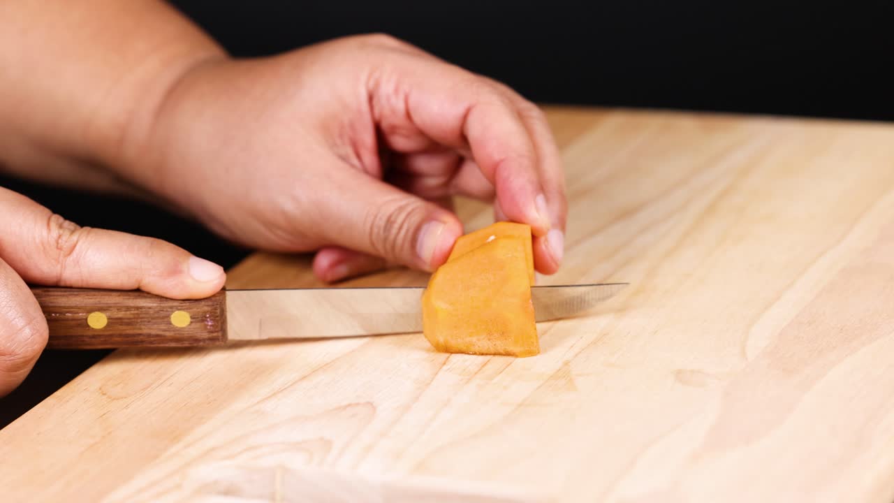 손은 칼로 파시몬을 잘라내고 있습니다.