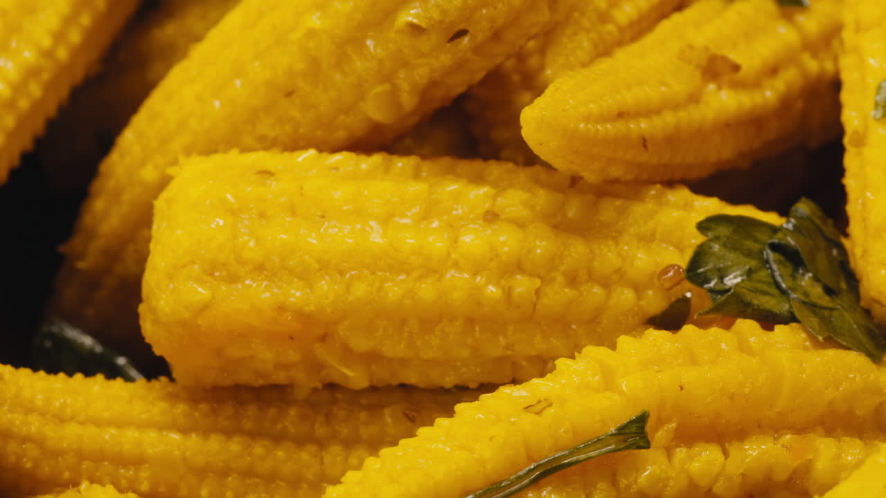 Close-up of fermented yellow mini corn with black pepper on plate. Preservation of vegetables in glass jars. Fermentation preserved mini corns with spices macro.