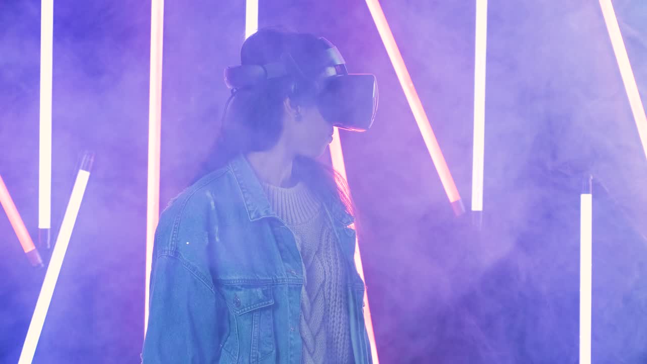 joven mira a su alrededor y se pregunta cómo increíble en la realidad virtual. casco de realidad virtual en color iluminación humo de fondo