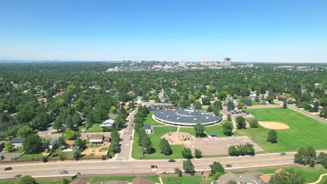 aerial drone pan of american elementary school surrounded by houses in neighborhood with cars driving on road