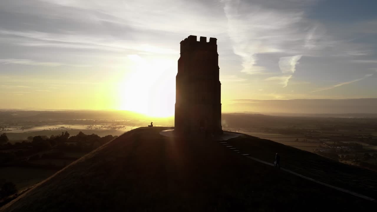 toma aérea ascendente de personas caminando por glastonbury tor al amanecer