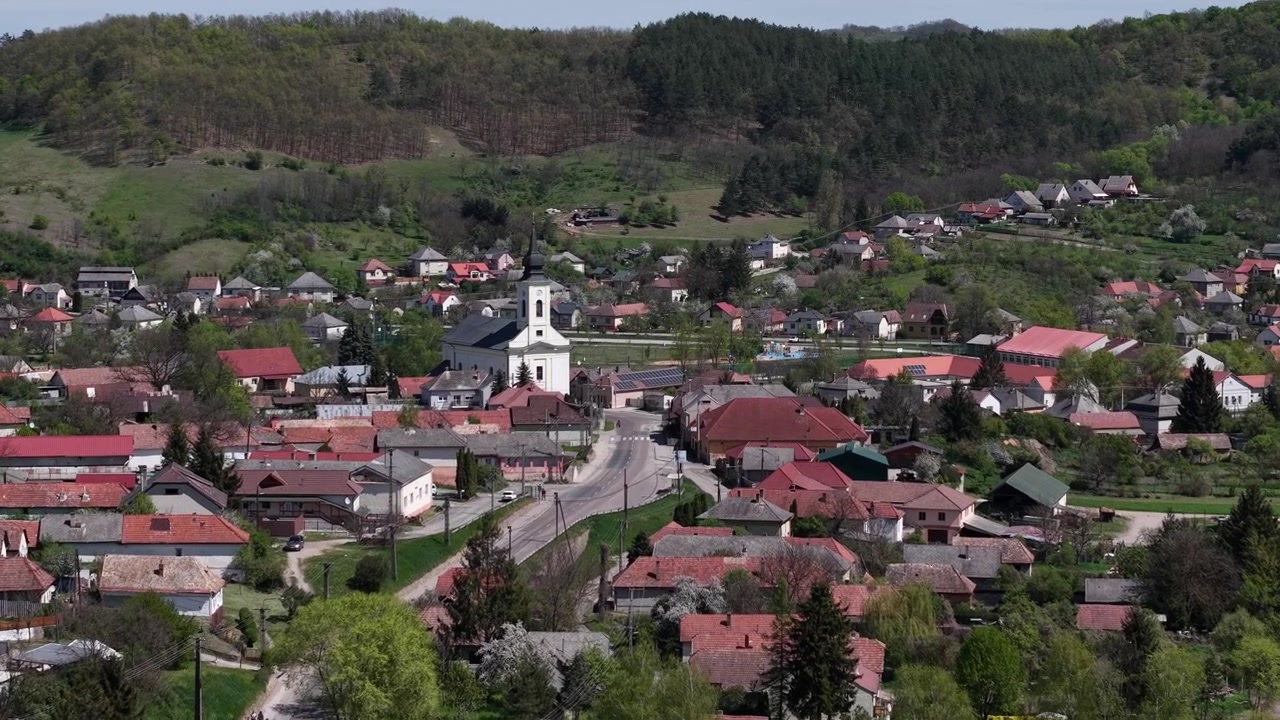 Okouzlující středoevropská vesnice a dominantní kostel, uhnízděné v bujných zelených kopcích a lesích, představují klidný jarní výhled.