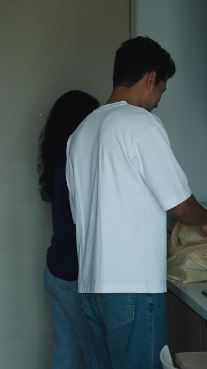 Pareja en la cocina con una bolsa de la compra