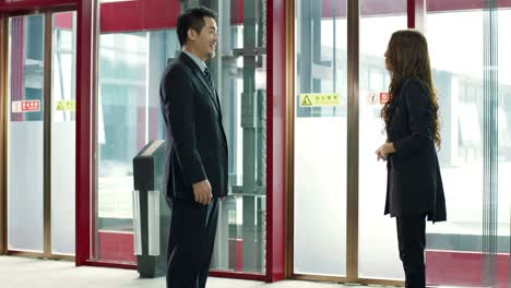 two asian business people standing and talking