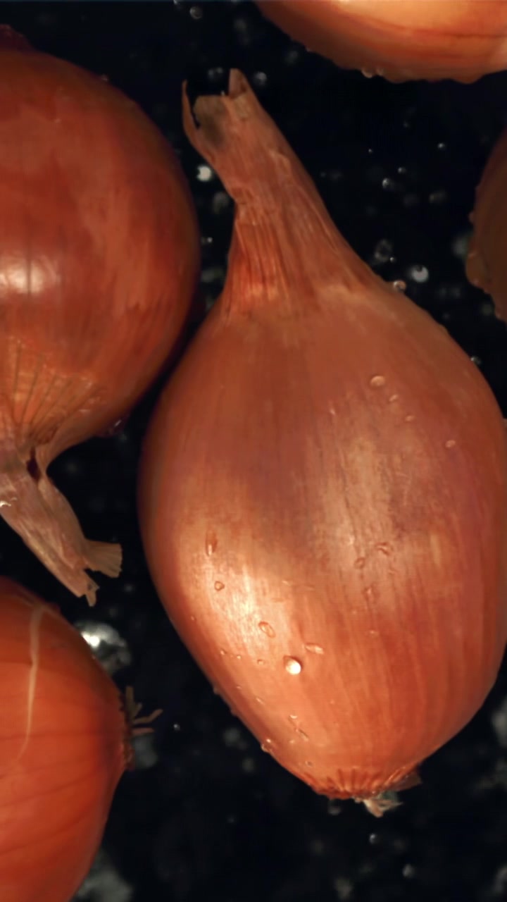 Primo piano di scalogni freschi con gocce d'acqua che schizzano su sfondo scuro