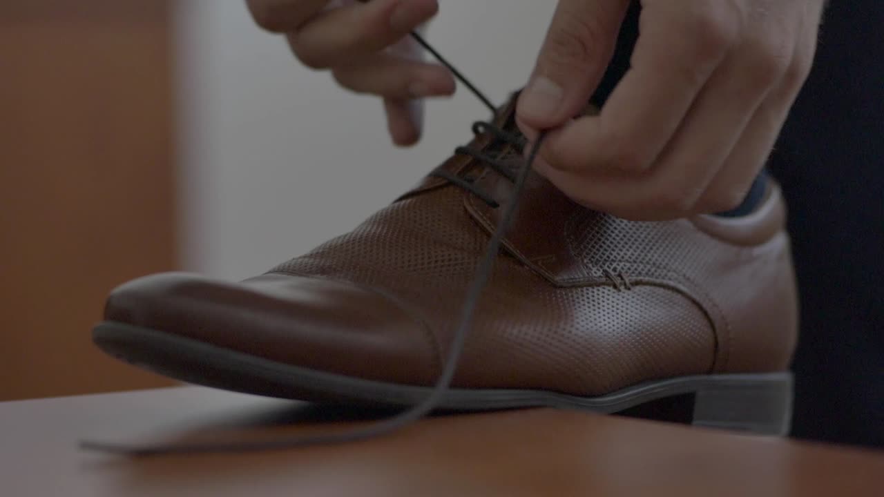 Close-up sepatu dan seorang pria sedang mengikat tali sepatu