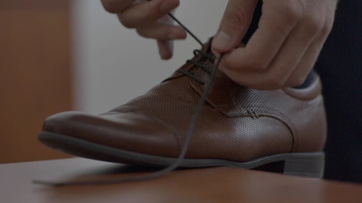 Close-up of a shoe and a man tying shoelaces
