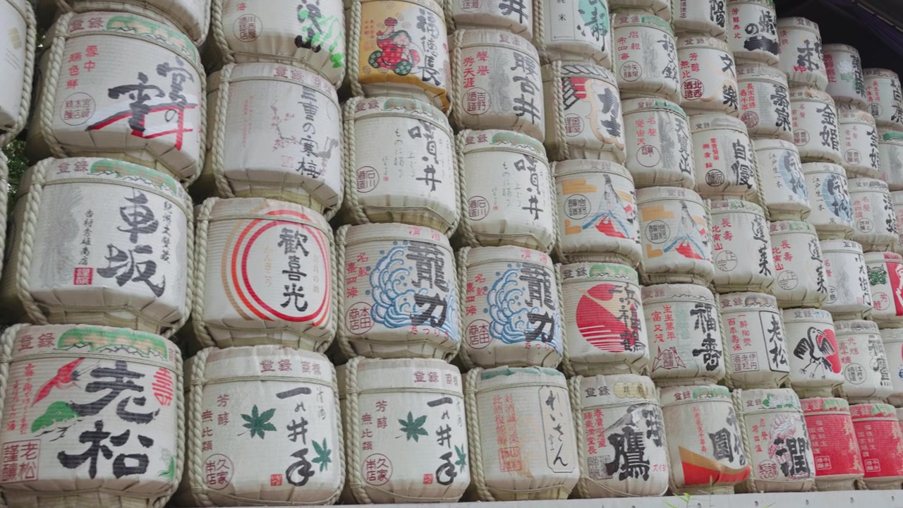 Panning gerak lambat di sepanjang tong sake berwarna-warni di Kuil Meiji Jingu pada siang hari di Taman Yoyogi di Tokyo