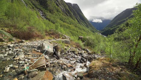 the foothills of the buarbreen glacier in the folgefonna national glacier park near odda, norway. a shallow stream rushing into the lush valley below. dark mountains tower on the horizon