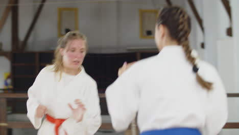 handheld shot of cute girls in kimono practicing karate in gym