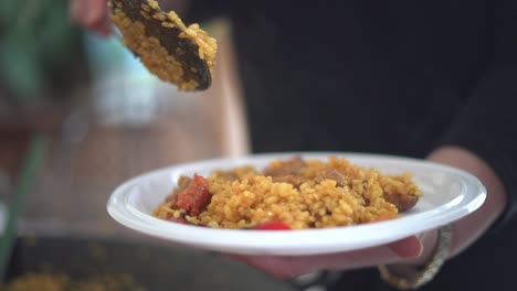 serving paella to a gathering of people celebrating