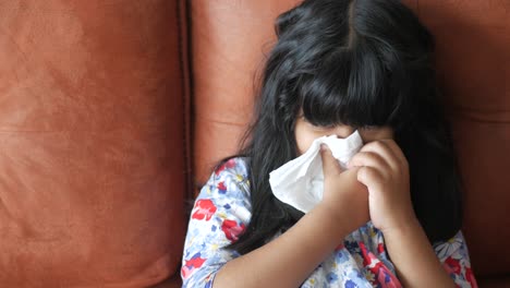 sick girl blowing nose on couch