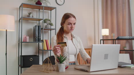 woman sitting at home using credit bank card and laptop pc while transferring money online shopping